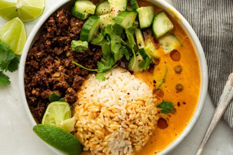 Beef broth bowl topped with chopped Persian cucumber, cilantro, sesame oil and fresh lime
