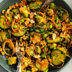 a large bowl full of crispy rice slaad with cucumbers, peanuts, avocado, red onions and crispy rice