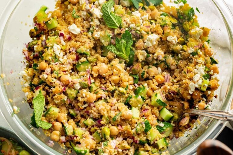 a large bowl of jennifer aniston salad topped with mint leaves and a lemon dressing