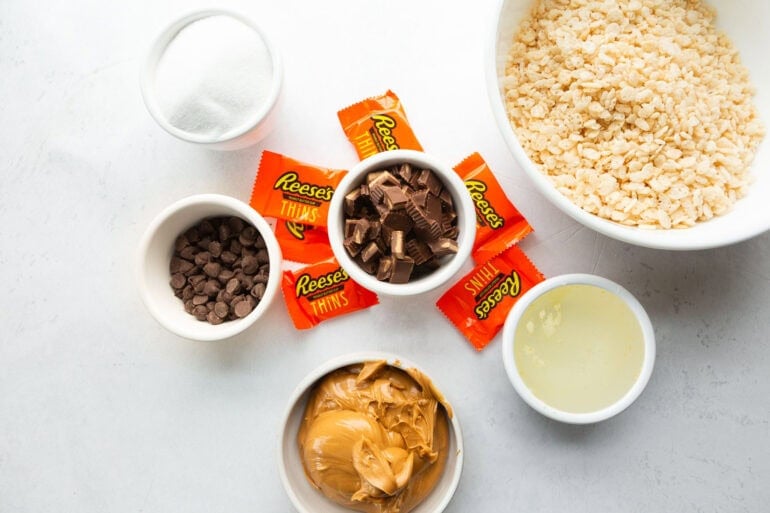 The ingredients for Reese's Krispies treats including Rice Krispies, chocolate chips, creamy peanut butter, and Reese's Cups
