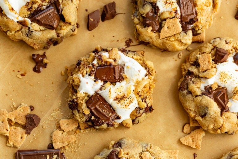 several gooey, melty chocolate s'mores cookies sitting on brown parchment paper
